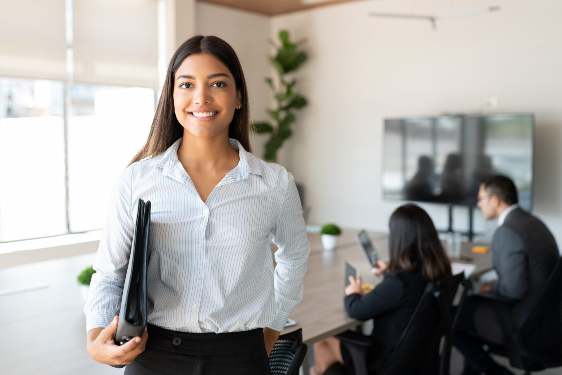 A woman holding a folder in an office.